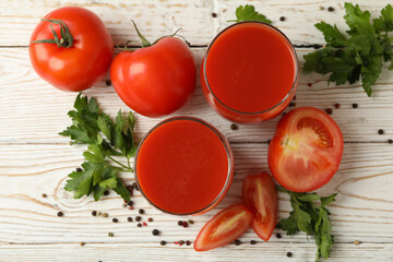 Glasses with tomato juice, tomatoes and spices on wooden background