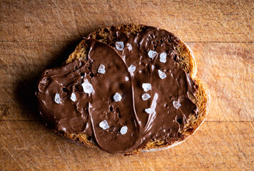 Slice of homemade bread with chocolate cream on the kitchen table for breakfast. Selective focus. Shallow depth of field. 
