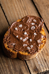 Slice of homemade bread with chocolate cream on the kitchen table for breakfast. Selective focus. Shallow depth of field. 
