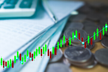 Candlestick Charts on blur image of coins, bank book, pen, calculator. for stock market analysis.