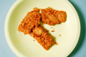fried tempeh on yellow plate with blue background