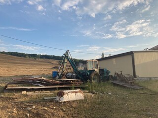 Rusty excavator working in countryside. Weathered excavator digging ground during agricultural works in field on summer day in countryside