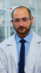 Portrait of exhausted chemist looking at camera in modern equipped lab. Multiethnic team examining virus evolution using high tech and chemistry tools for scientific research, vaccine development.