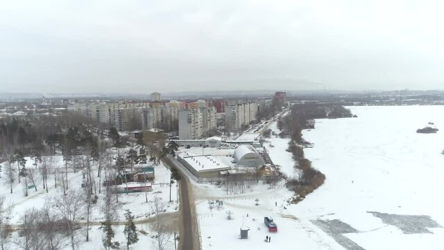 Flying over a frozen lake in the city. The forest belt. Aerial photography
