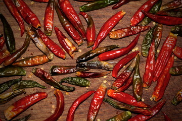 Red dried chili peppers sprinkled on a wooden board. soft selective focus. Vignetting filter.