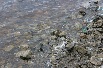 Stones on the beach with broken bottles