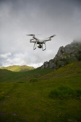 Fototapeta na wymiar UAV drone in flight over a mountain landscape in a cloudy day