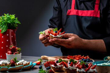chef preparing desserts at table in kitchen. cooking berry dessert tarts with cheese cream