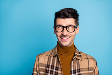 Portrait of young handsome dreamy cheerful positive smiling man in glasses look copyspace isolated on blue color background