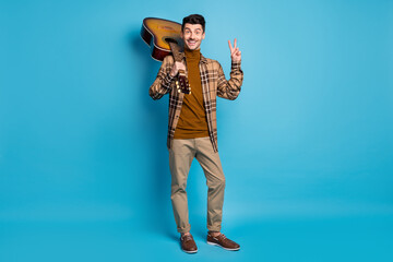 Full size photo of young happy smiling positive man showing v-sign hold guitar on shoulder isolated...