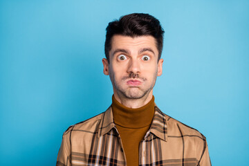 Fototapeta premium Portrait of young shocked surprised amazed funky man staring hold breath wear checkered shirt isolated on blue color background