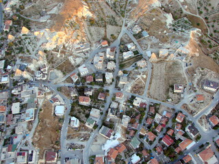 View from the height of the balloon on the various roofs of numerous houses of the mountain settlement under the first rays of sunrise.