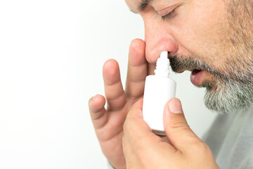 Man applying spray for runny nose, treatment of colds and flu concept