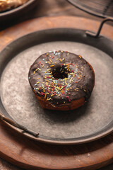 Chocolate frosted donut with colorful festive sprinkles kept in rustic iron plate