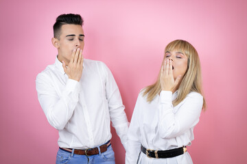 Obraz premium Young couple of girlfriend and boyfriend over isolated pink background bored yawning tired covering mouth with hand. Restless and sleepiness.