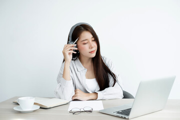 Video call, a young Asian woman wearing headphones, communicates via online video long distance, looking at the digital laptop screen, happily greeted with a friend