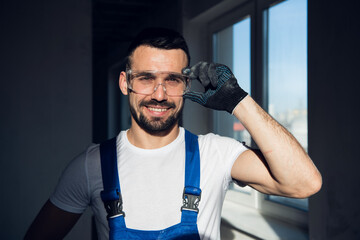 Bearded builder adjusts protective glasses and smiles