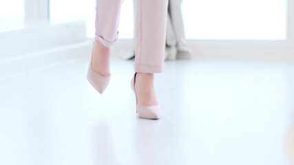 Fashionable woman wearing high heel shoes. Fashionable woman in high-heeled shoes. soft focus woman walking on white wooden floor.