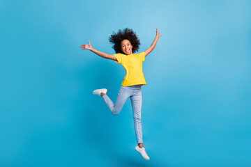 Full body photo of happy afro american girl raise hands jump wear yellow t-shirt jeans isolated on...