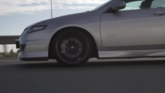 Side view of modern powerful car rides on summer highway. Footage. Perfect auto drives fast on country road.