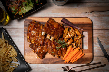 Grilled sliced barbecue pork ribs on wooden plate. Delicious Pork Spare Ribs BBQ seasoned with a...