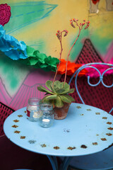 Blue metail outdoor table and chair set with a small succulent in a pot and candles in glass jars