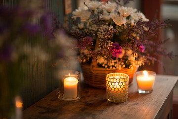 Candles in glass jars with flames burning sitting on a sideboard
