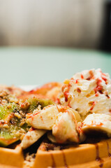 Belgian waffle with fruits whipped cream and syrup on top of it
