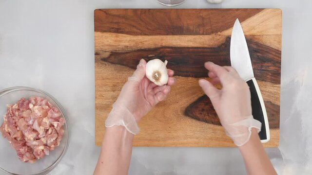 Chef peeling garlic on wooden board. Sour cream chicken paprika recipe, step by step cooking process, part of series.