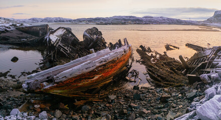 An old rusty fishing boat abandoned by a storm on the shore. Graveyard of ships, old fishing village on the shore of the Barents sea, the Kola Peninsula, Teriberka