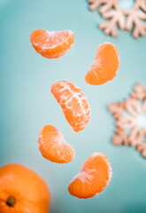 tangerines on a blue background. orange tangerine with slices and wooden Christmas tree decor on the table. wooden snowflakes and tangerines on the table