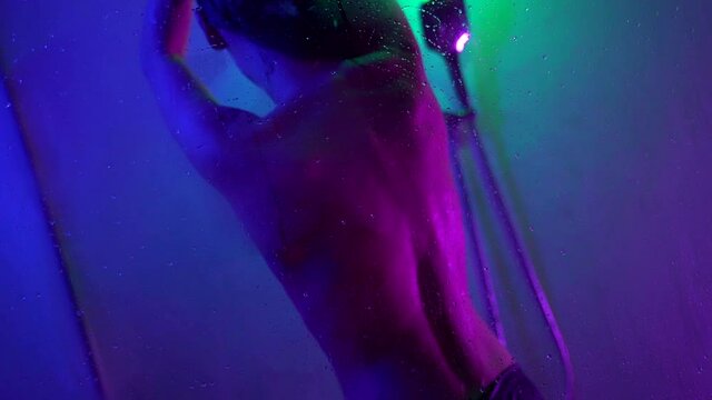 a young woman poses in a shower stall. the view of a young sexy woman in a bare top, standing with her back to us.