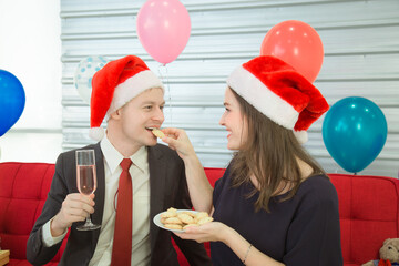 A man and woman wearing a Christmas hat hold a Champagne glass to celebrate Xmas day.