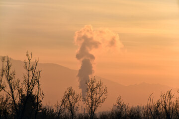 Chimney of a thermal power plant on the evening sky at sunset