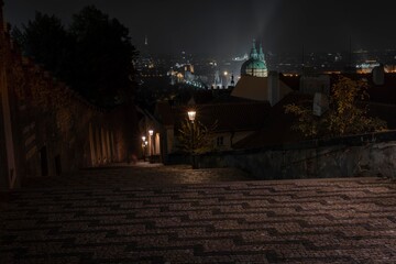 .street lights and pedestrian sidewalk with cobblestones in the center of Prague at night and in the background city view at night