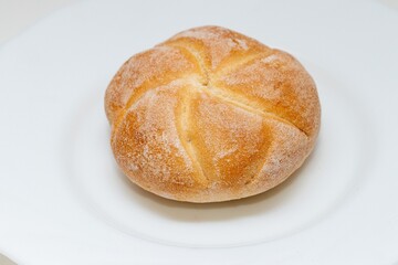 Chubby fresh round bun made of white flour on a plate