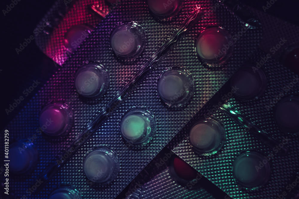 Aufkleber pills or drugs in a package under neon light on a dark background pattern for design..
