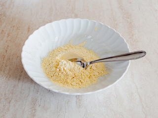 Chickpea flour in a bowl of white porcella. Vegan ingredient for batters, pancakes
