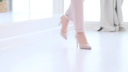 Fashionable woman wearing high heel shoes. Fashionable woman in high-heeled shoes. soft focus woman walking on white wooden floor.