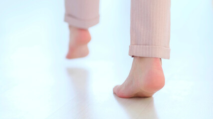Side close up view of unrecognizable woman feet legs, barefoot girl standing indoors inside of modern home enjoy warm wooden heated floor. soft focus