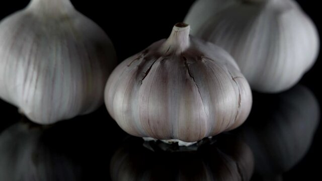 close-up of organic three heads of garlic on a table isolated on a dark background.