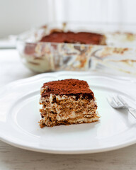 Close up on a portion of vegan tiramisu. Italian dessert on a white plate on wooden table
