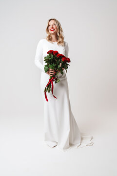 Smiling beautiful blonde girl in elegant dress posing with roses
