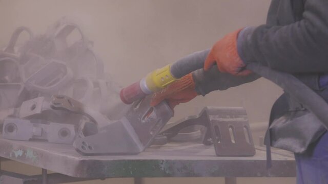 Sandblast metal parts. The man is sandblasting the detail. Sandblasting gun