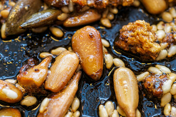 Assorted seeds being fried in oil in a frying pan