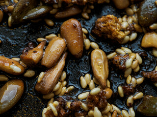 Assorted seeds being fried in oil in a frying pan