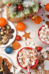 sweet food top view background for merry christmas or new year holiday decoration - chocolate candies, tangerines, cookies, marshmallow and cocoa latte on white wood