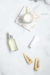 Hair care cosmetics kit and women's hairpins on marble table. Flat lay, view from above.