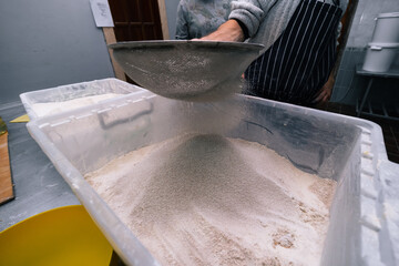 Flour sifting through a sieve for a baking. man hands, industrial