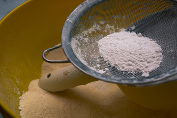 Flour sifting through a metal sieve for a baking. Close up.